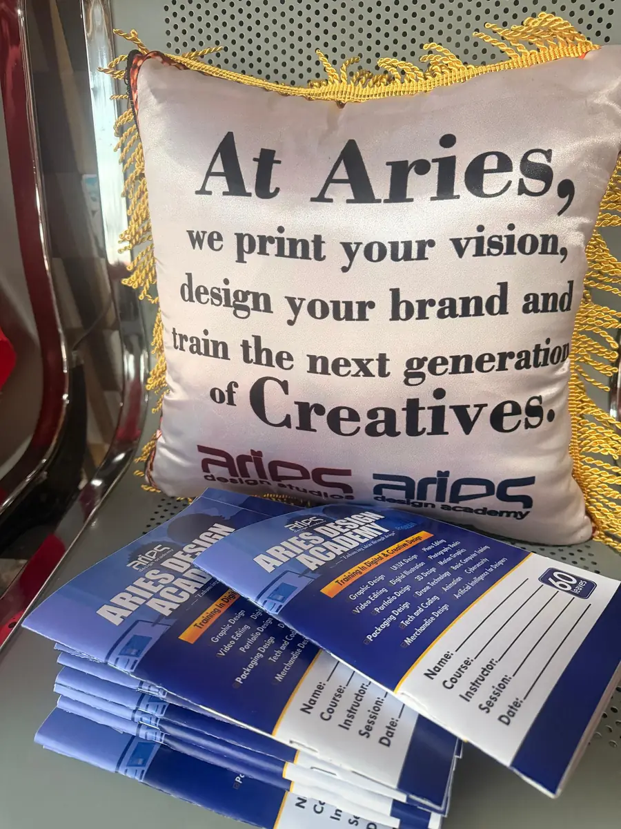 An Aries cushion that reads: At Aries, we print your vision, design your brand and train the next generation of creatives, beside Academy brochures